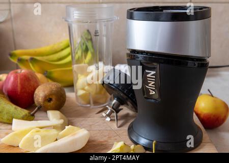 Londres. ROYAUME-UNI- 04.19.2023. Une centrifugeuse Ninja avec divers fruits sur une planche à découper de cuisine. Banque D'Images