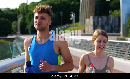 Bel homme et belle femme qui s'entraîner dans la rue et qui court ensemble sur le pont avec une belle vue. Gros plan de la course mâle et femelle caucasienne active Banque D'Images