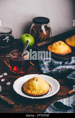 Mini tarte aux pommes maison sur plaque blanche avec une tasse de thé noir Banque D'Images