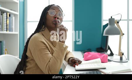 Femme africaine lisant un livre demandant le silence à l'université de bibliothèque Banque D'Images