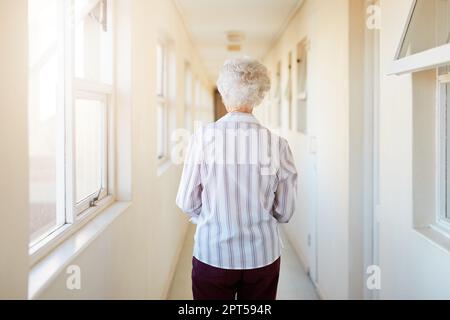 Où elle appelle maintenant à la maison. Vue arrière d'une femme âgée marchant dans un couloir dans une maison de retraite Banque D'Images