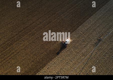 un agriculteur qui conduit un tracteur à chenilles tire un nuage de poussière derrière lui, labour, casse-croûte de surface de hersage pour faciliter la naissance et l'ensemencement o Banque D'Images