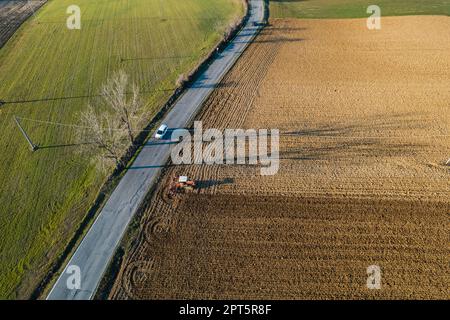 un agriculteur qui conduit un tracteur à chenilles tire un nuage de poussière derrière lui, labour, casse-croûte de surface de hersage pour faciliter la naissance et l'ensemencement o Banque D'Images