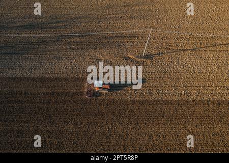 un agriculteur qui conduit un tracteur à chenilles tire un nuage de poussière derrière lui, labour, casse-croûte de surface de hersage pour faciliter la naissance et l'ensemencement o Banque D'Images