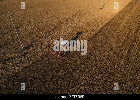 un agriculteur qui conduit un tracteur à chenilles tire un nuage de poussière derrière lui, labour, casse-croûte de surface de hersage pour faciliter la naissance et l'ensemencement o Banque D'Images