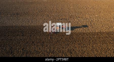 un agriculteur qui conduit un tracteur à chenilles tire un nuage de poussière derrière lui, labour, casse-croûte de surface de hersage pour faciliter la naissance et l'ensemencement o Banque D'Images