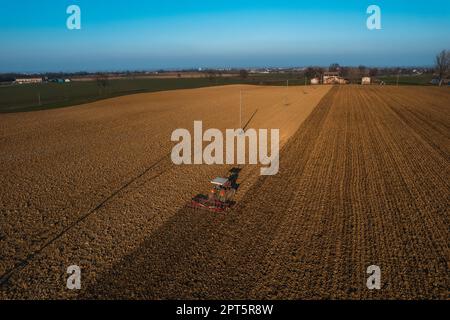 un agriculteur qui conduit un tracteur à chenilles tire un nuage de poussière derrière lui, labour, casse-croûte de surface de hersage pour faciliter la naissance et l'ensemencement o Banque D'Images