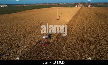 un agriculteur qui conduit un tracteur à chenilles tire un nuage de poussière derrière lui, labour, casse-croûte de surface de hersage pour faciliter la naissance et l'ensemencement o Banque D'Images