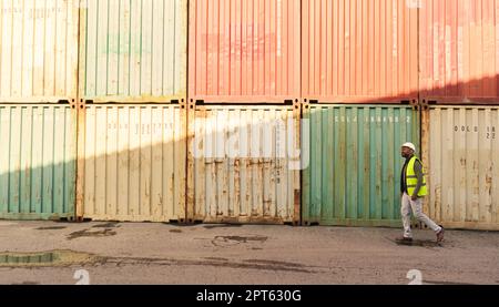 Expédition, travailleur de la logistique dans le port de chantier naval et marche par les conteneurs de fret. Transport de marchandises commerciales, livraison internationale et invento Banque D'Images