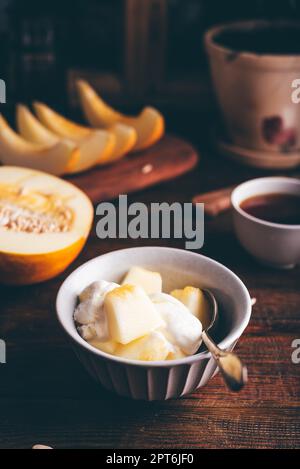 Dessert de glace à la vanille mélangé avec du melon de miel haché dans un bol Banque D'Images