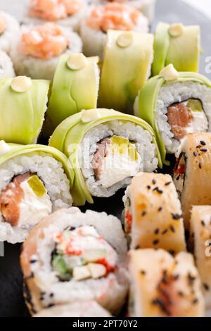 Cuisine asiatique. Un grand ensemble de sushis de divers petits pains à sushis est servi sur une ardoise métallique carrée noire. Vue latérale de différents rouleaux avec variété de fraîcheur ingred Banque D'Images