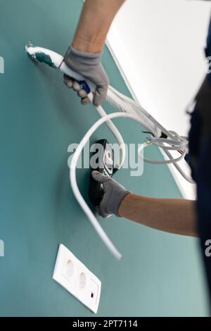 Mesure sur le chantier. Handyman fait le câblage et installe la climatisation pendant les réparations dans le nouvel appartement. Gros plan du mode de connexion de l'employé Banque D'Images