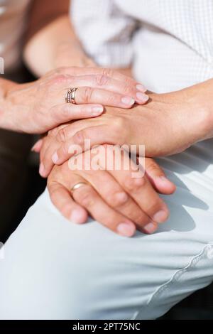 Partager leur vie. un couple senior se repose les mains les unes sur les autres avec leurs anneaux de mariage montrant Banque D'Images