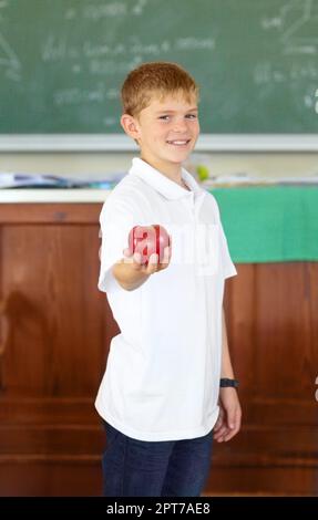 Animaux de compagnie des enseignants. Un jeune écolier mignon tenant une pomme dans la salle de classe Banque D'Images