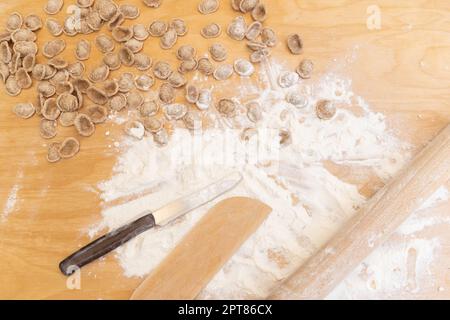 Préparation de l'orecchiette de pâtes du sud de l'italie en plein air sur le plan d'examen en bois. Pâtes maison fraîches traditionnelles de la région des pouilles. Régime méditerranéen i Banque D'Images