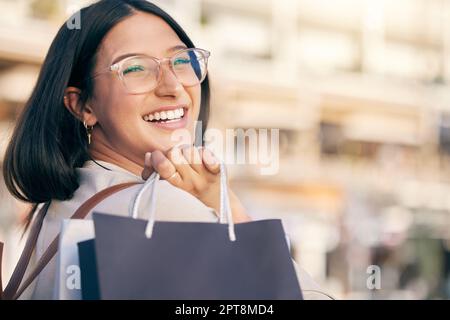 Dépensez moins, achetez plus. Portrait d'une jeune femme attrayante marchant seule à l'extérieur tout en faisant du shopping dans la ville Banque D'Images