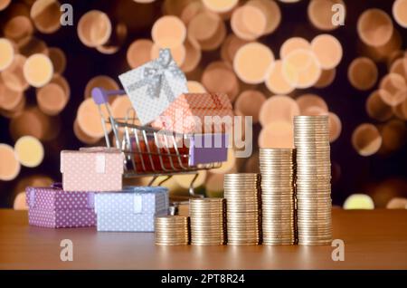 De nombreux coffrets cadeaux dans votre panier et golden coins cheminées sur l'arrière-plan flou de couleur. Shopping et vente de noël concept Banque D'Images