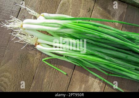 Bande d'oignons verts frais sur une vieille table en bois. Banque D'Images