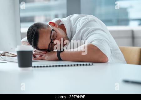 Quelle journée il a été. un jeune homme d'affaires travaillant dans un centre d'appels qui fait une sieste Banque D'Images