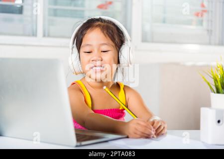 Petit enfant porter un casque d'enfant assis au bureau utiliser ordinateur portable et communique sur Internet appel vidéo en ligne avec le professeur, enfant asiatique fille Stud Banque D'Images