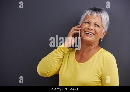 C'est tellement bon d'entendre de vous. Une femme mûre parlant sur un téléphone mobile dans un studio Banque D'Images