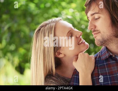 Jeune et plein de passion. Portrait d'un jeune couple souriant qui s'embrasse dans le parc Banque D'Images