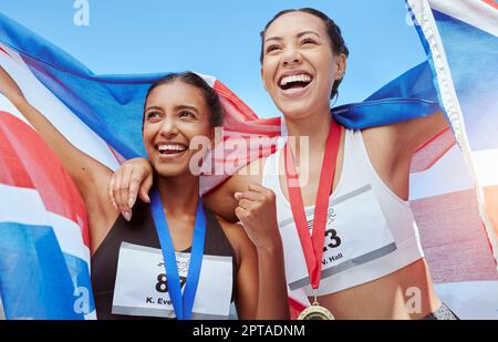 Succès, femmes et équipe de course avec un drapeau en célébration des gagnants médailles réalisation dans un événement sportif. Fitness, athlètes britanniques et heureux Banque D'Images