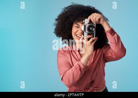 Vous me donnez des souvenirs incroyables pour ma collection. Photo en studio d'une jeune femme utilisant un appareil photo sur fond bleu Banque D'Images