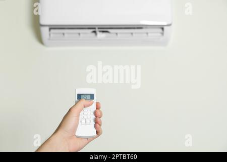 Homme utilisant le climatiseur avec télécommande à l'intérieur, gros plan Banque D'Images