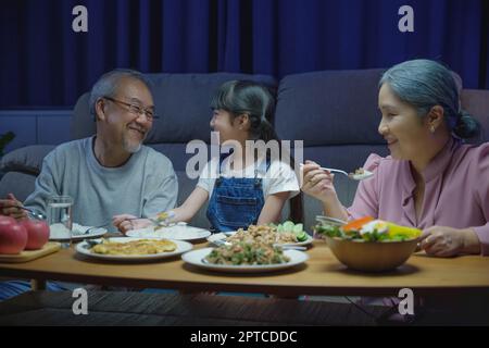 Happy Asian famille grand-parents et petite-fille dîner sur table et s'amuser pendant la maison soir, parent senior et enfant de bonheur manger Banque D'Images