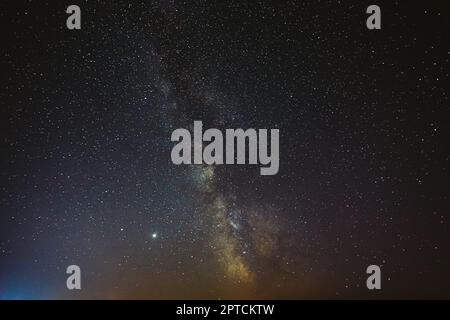 Ciel étoilé de nuit avec étoiles brillantes. Lueur brillante des planètes Saturne et Jupiter dans le ciel parmi les étoiles de la voie lactée Galaxy. Ciel dans les lumières de l'aube au coucher du soleil. Banque D'Images