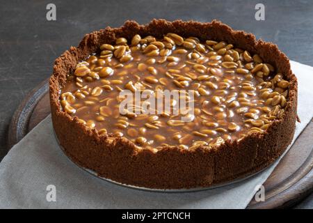 Cheesecake au caramel et aux arachides maison sur fond sombre. Délicieux gâteau de boulangerie le matin. Banque D'Images