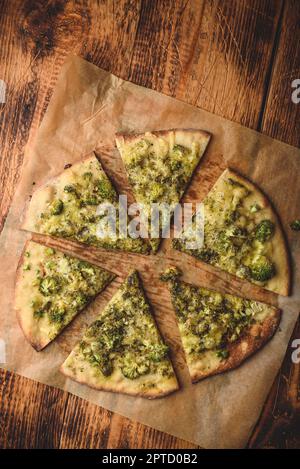 Pizza au brocoli et au fromage cuite et coupée en tranches sur du papier de cuisson. Vue de dessus Banque D'Images