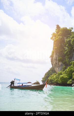 Juste un autre jour au paradis. un homme debout sur un bateau flottant dans les eaux tropicales Banque D'Images