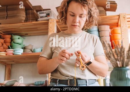 Femme en bois naturel sûr sur le bureau, style écologique. Perles de cerclées. Jouet de dentition avec décoration de ferraillement de cercueil. Travail de fabrication à la main de à Banque D'Images