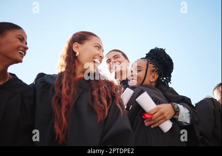 Étudiants, hug et certificat de remise des diplômes succès dans la cérémonie de célébration sur le campus de l'école, de l'université ou du collège. Faible angle, diversité des amis ou grad Banque D'Images