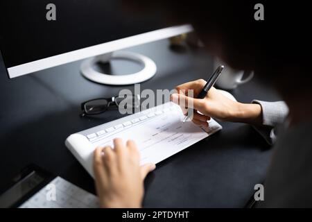 Une femme africaine signant un chèque de banque ou un chèque de paie Banque D'Images