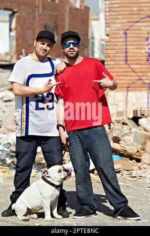 Amis pour la vie. Deux gangsters debout dans leur quartier avec leur chien Banque D'Images