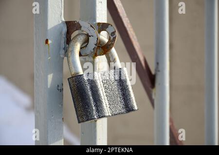 Un grand cadenas gris est suspendu à une porte en métal Banque D'Images