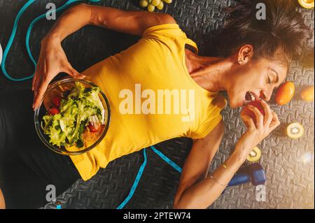 Une femme mange en bonne santé et s'entraîne dans la salle de gym Banque D'Images