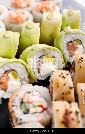 Cuisine asiatique. Un grand ensemble de sushis de divers petits pains à sushis est servi sur une ardoise métallique carrée noire. Vue latérale de différents rouleaux avec variété de fraîcheur ingred Banque D'Images