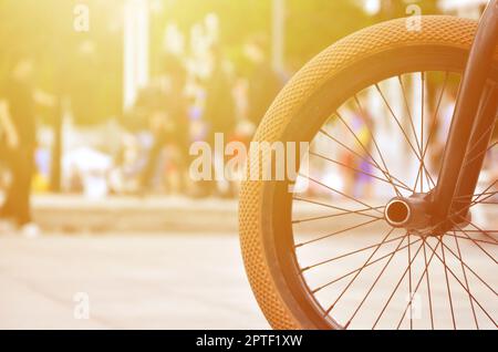 Une roue de vélo BMX dans le contexte d'une rue avec des coureurs cyclistes brouillée. Extreme Sports Concept Banque D'Images