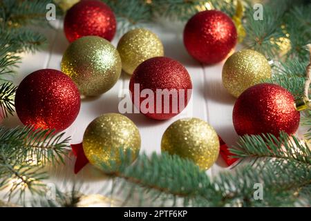 Branches vertes d'un sapin de Noël avec ampoules LED, guirlande et boules brillantes sur fond blanc en bois. Joyeux Noël et bonne année conc Banque D'Images