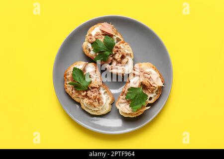 Assiette avec savoureux bruschettas de thon sur fond jaune Banque D'Images