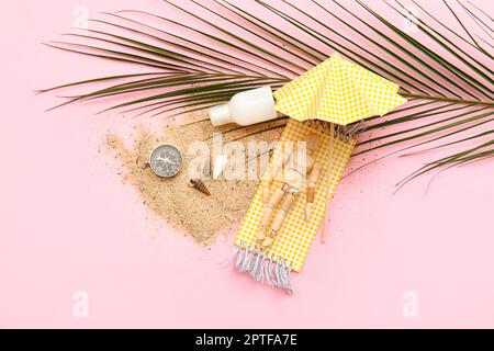 Composition avec coquillages, compas, feuille de palmier et mannequin en bois couché sur une serviette de plage sur fond rose Banque D'Images