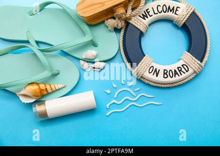 Composition au soleil en crème solaire, bouée circulaire, avion en bois, tongs et coquillages sur fond bleu Banque D'Images