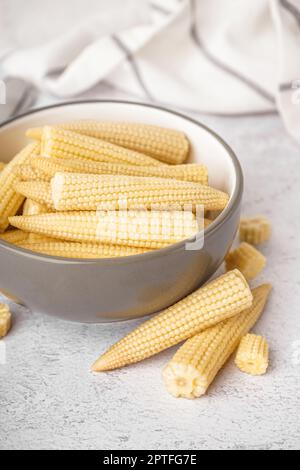 Bol avec de savoureux épis de maïs en conserve sur fond clair Banque D'Images