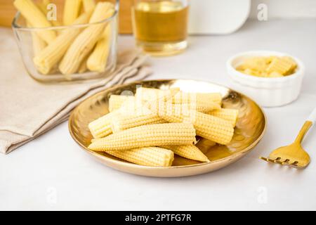 Assiette avec de savoureux épis de maïs en conserve sur fond clair Banque D'Images