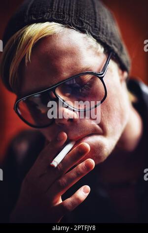 Prendre un glissement. Un jeune homme en ville allume une cigarette Banque D'Images