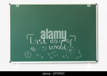 Tableau noir avec texte LE DERNIER JOUR DE L'ÉCOLE et dessins sur le mur blanc Banque D'Images